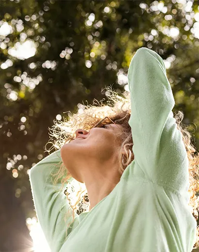 Une personne en paix, se détendant dans la nature, éclairée par la lumière du soleil.