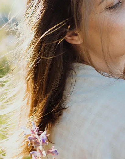 Profil latéral apaisant avec cheveux éclairés par le soleil et fleur de lavande, évoquant la relaxation et l’hypnose.